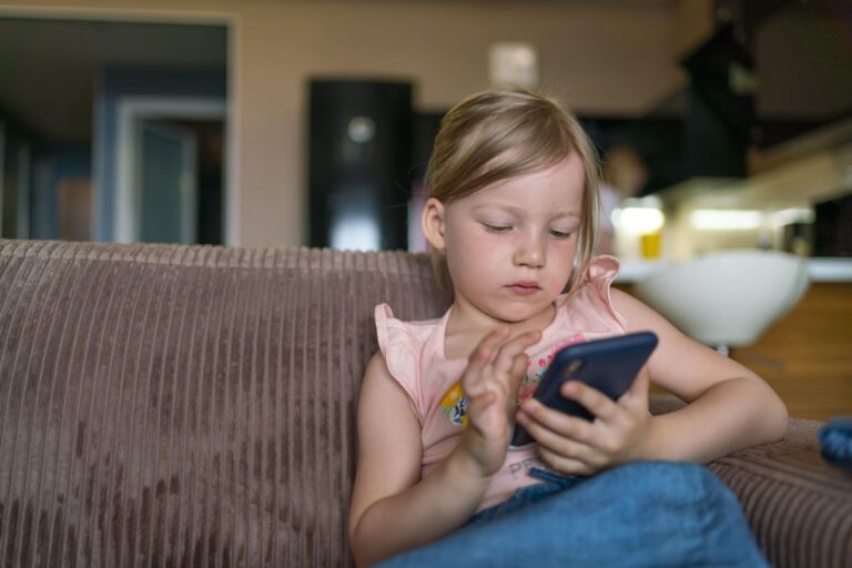 Menina loira fazendo uso excessivo do celular.