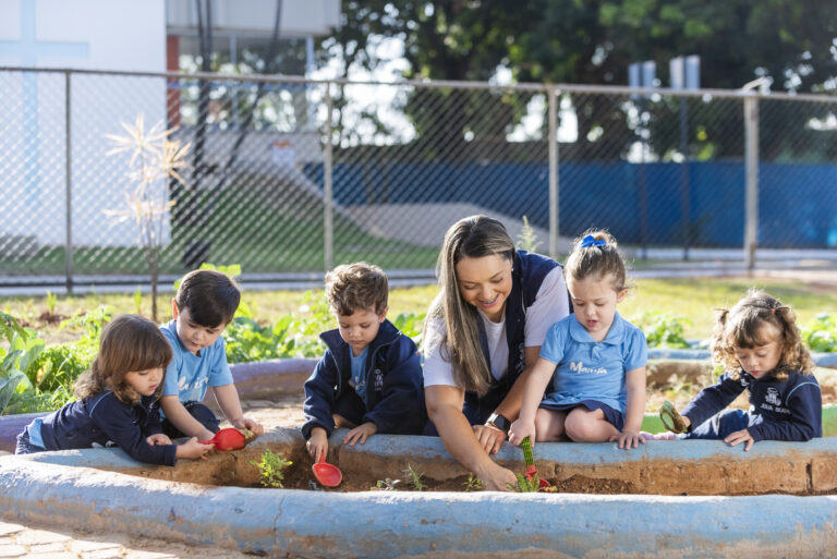 Desenvolvimento infantil: professoras com as crianças fazendo uma horta.