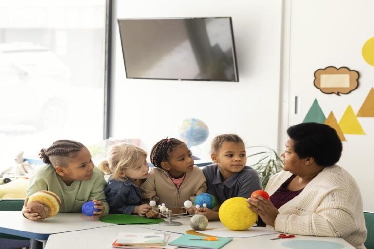 educação antirracista: uma professora dando aula as crianças no fundo, tem uma televisão.