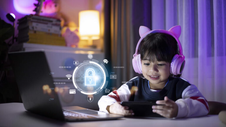 Criança com fone de ouvido utilizando o computador e celular com ilustração de cadeado à frente da tela, representando a segurança na internet.